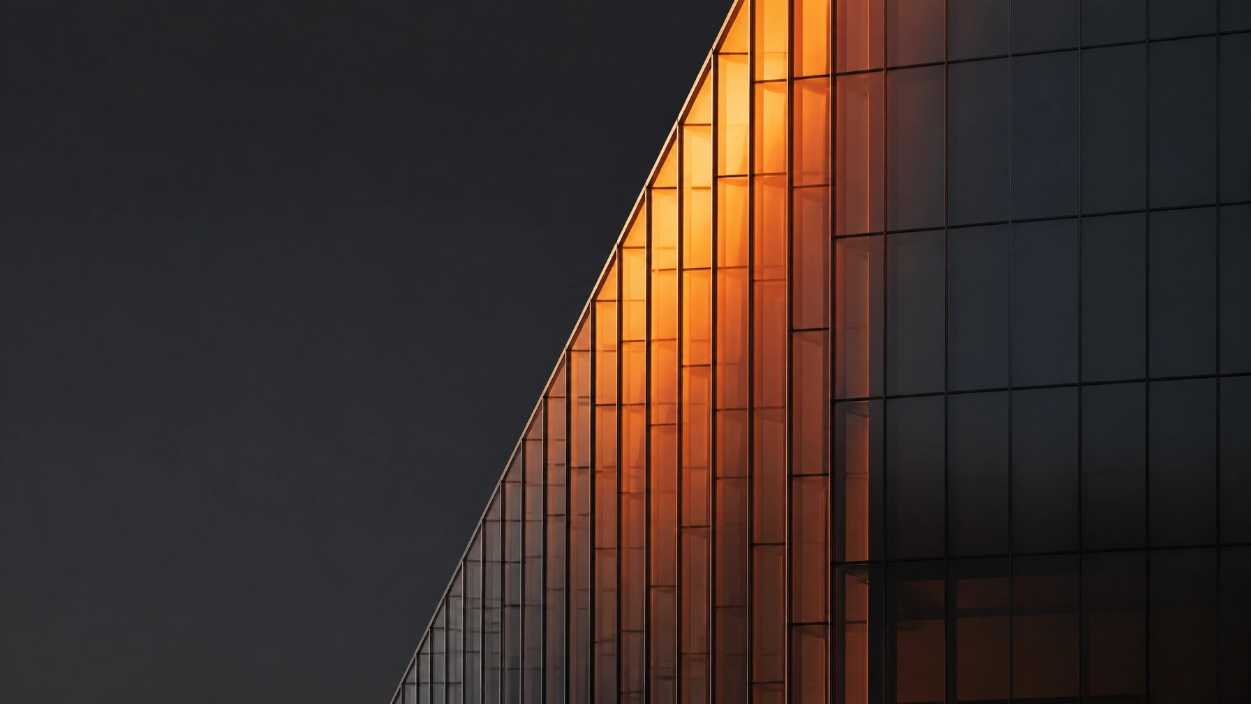 Abstract architectural photography of a modern glass building with orange light reflecting off geometric lines
