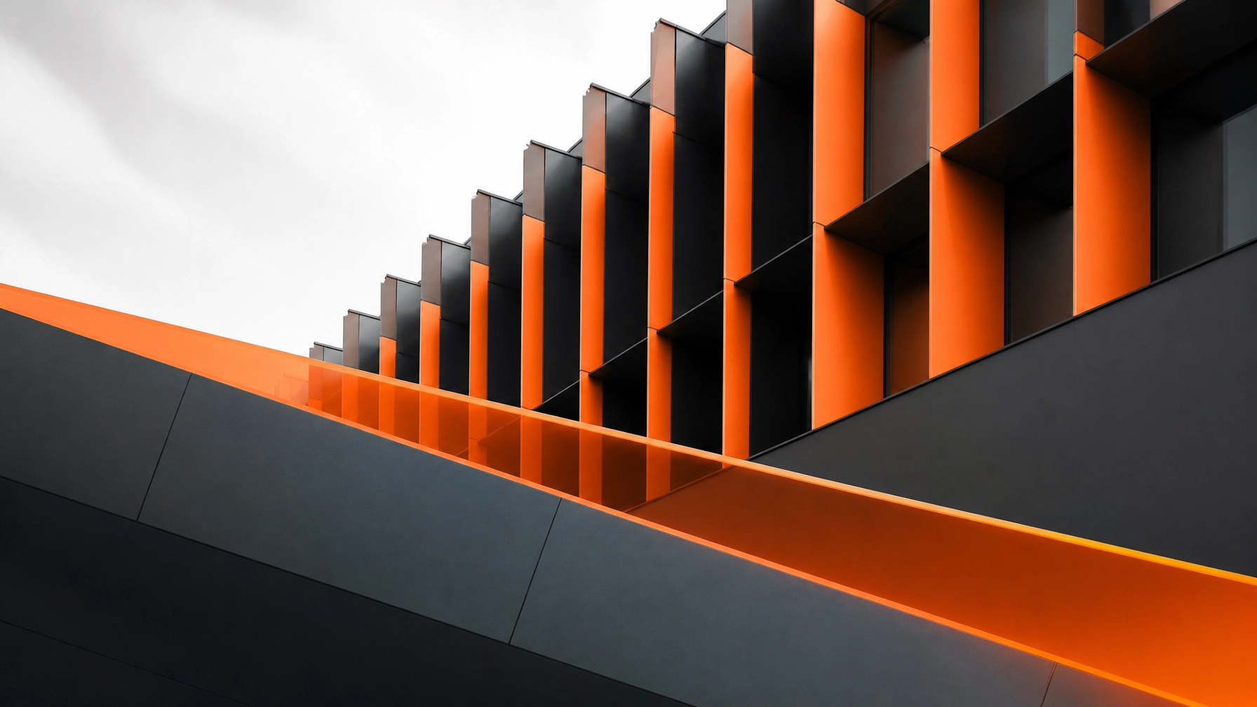 Abstract architectural photography with clean geometric patterns and a vibrant orange gradient against charcoal gray, representing technical structure and innovation.
